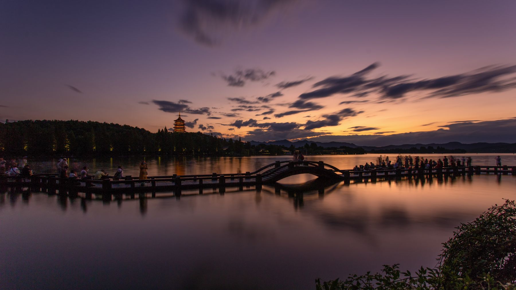 Pôr do sol no Lago Oeste, em Hangzhou, com o Pagode Leifeng iluminado e reflexos de tons quentes na água